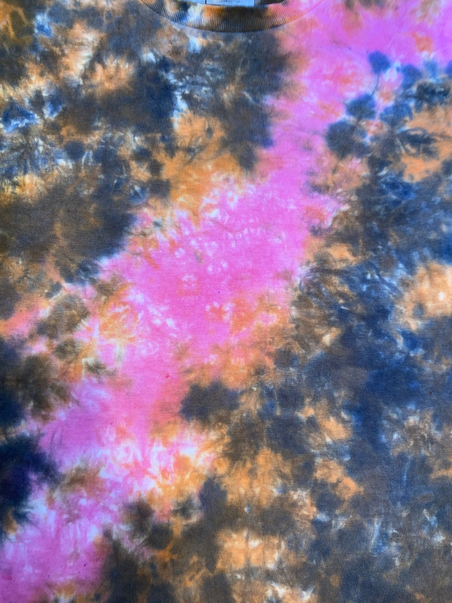 Tie-dye t-shirt with pink diagonal messy line like a space nebula with orange and black partterns each side
