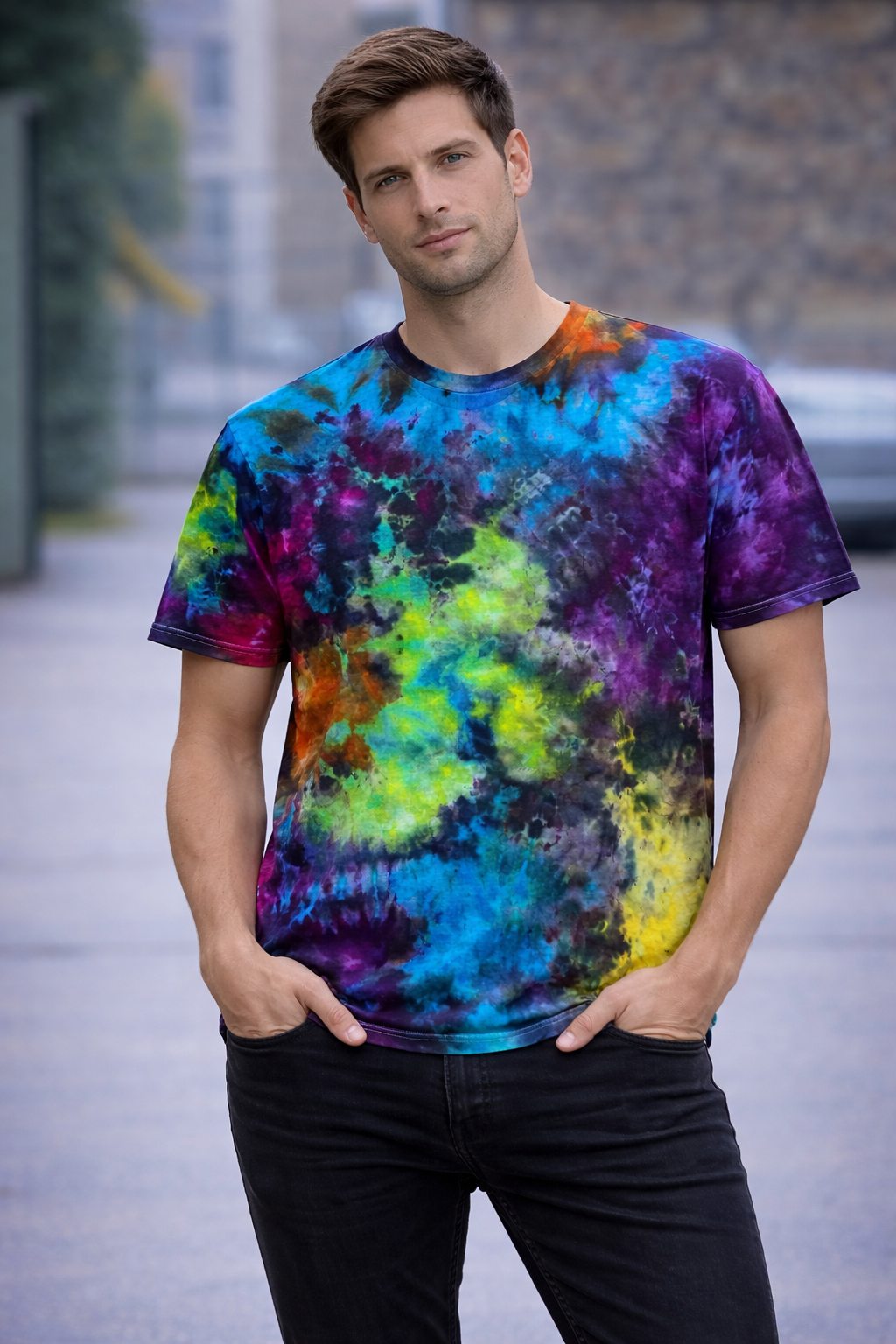 Man wearing a colorful tie-dye t-shirt standing outdoors.