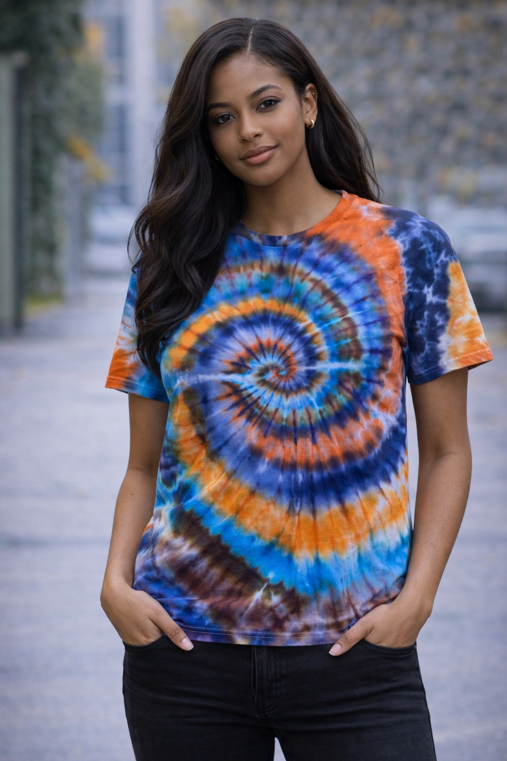 Woman wearing a tie-dye shirt with a spiral pattern outdoors.