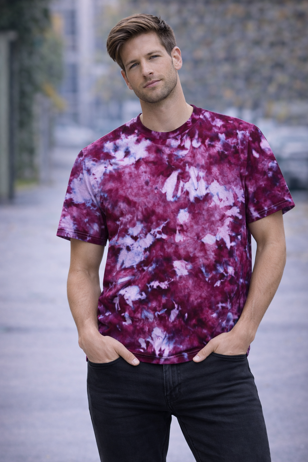 Man wearing a tie-dye t-shirt with a blurred outdoor background