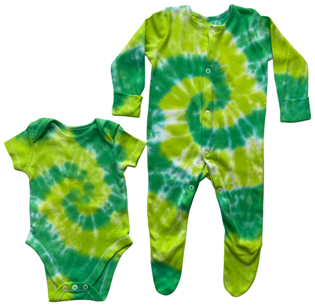 A matching baby clothing set featuring a short-sleeve bodysuit and a long-sleeve footed sleeper, both in a vibrant green and yellow tie-dye spiral pattern, displayed on a solid white background.