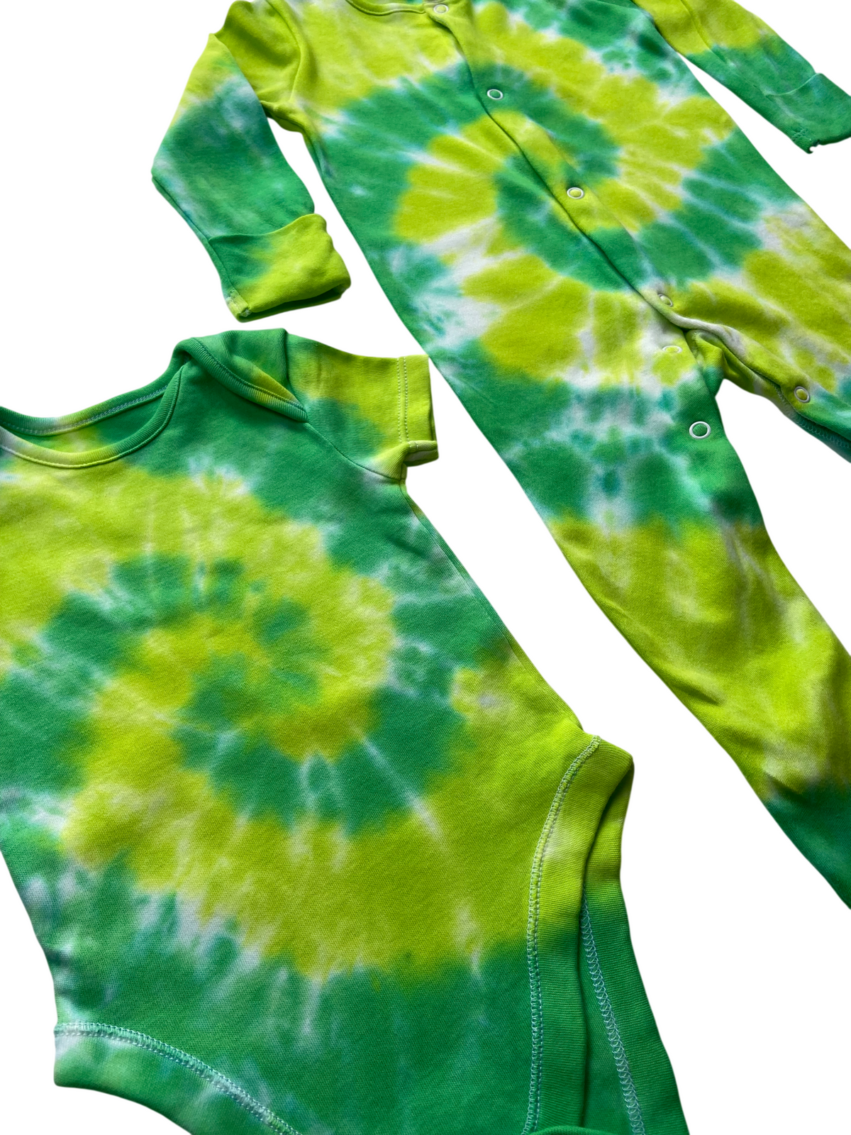 A baby clothing set featuring a green and yellow tie-dye long-sleeve one-piece and a matching short-sleeve bodysuit, laid flat on a white background.