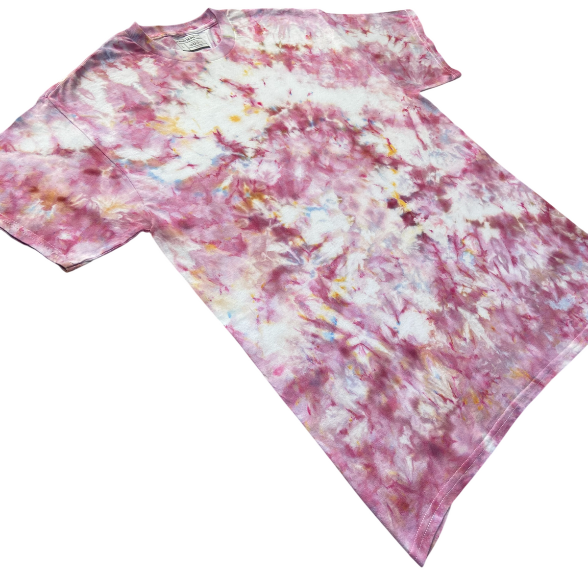 Angled view of the Powder Pink Ice Scrunch tie dye T-shirt in soft pink, dusty rose and white with subtle blue and yellow accents, showing the hand dyed scrunch pattern on a white background.