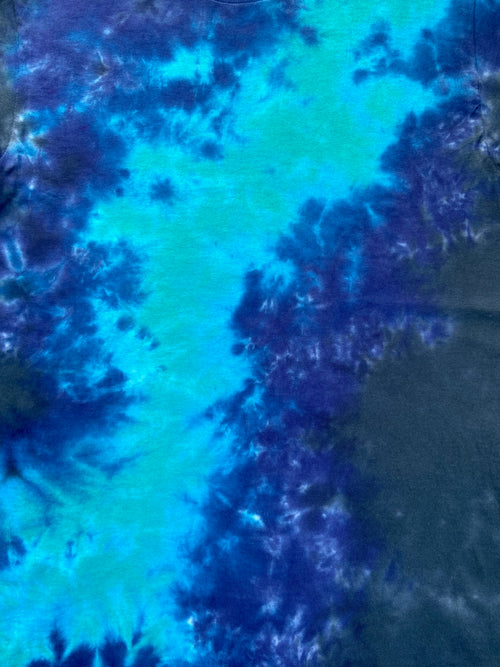 A close-up of a tie-dye fabric with a vertical band of bright turquoise and deep blue, surrounded by dark navy and purple mottled patches.