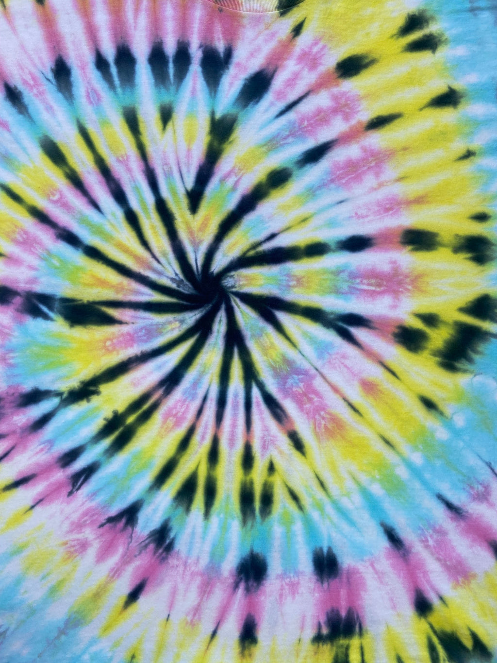 Summer pastel spiral tie dye T-shirt in yellow, pink and blue with a bold black spiral pattern, hand dyed in the UK by Essex Tie Dye.