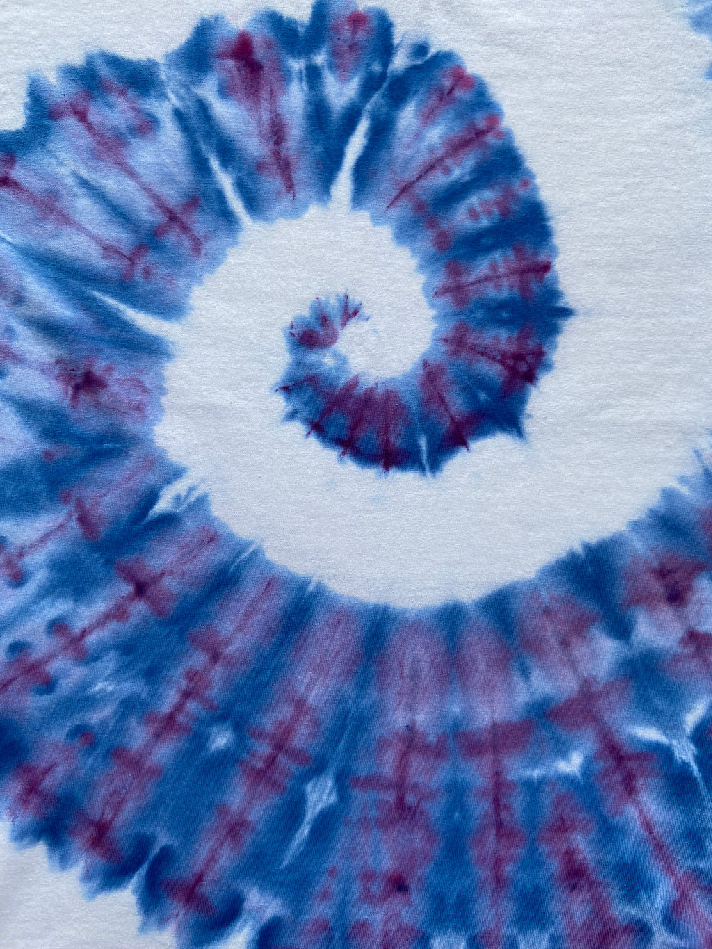 Tie-dye pattern with blue and red swirls on a white background