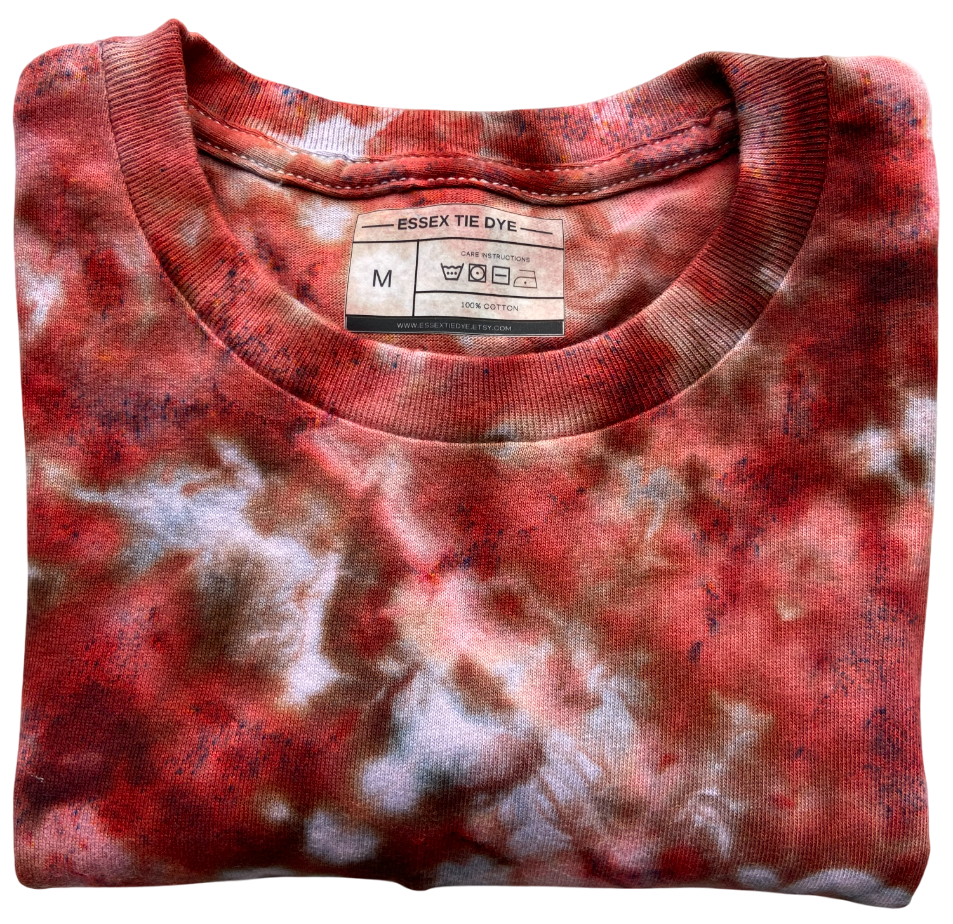Folded red and white tie-dye shirt with a label on a white background