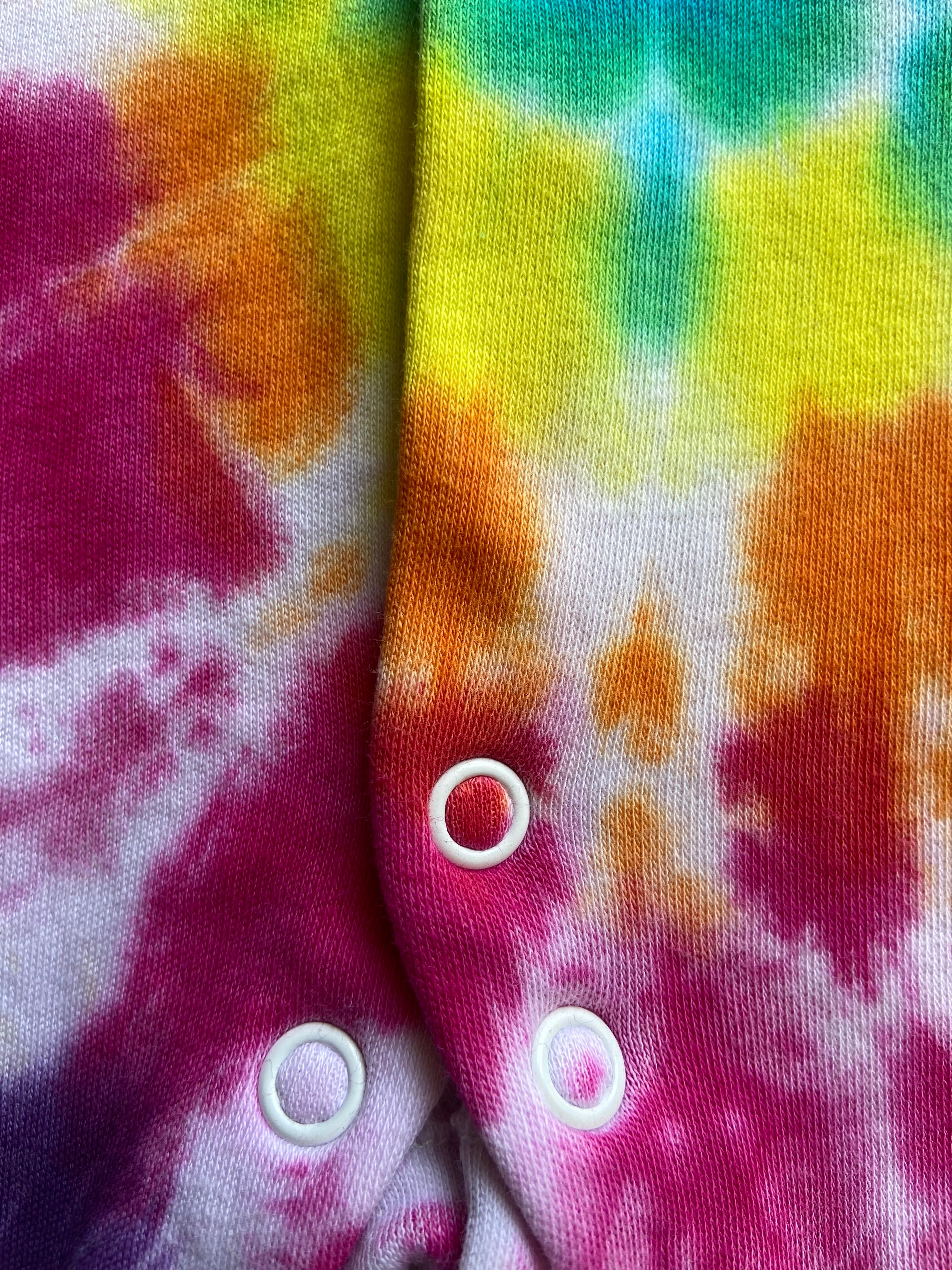 Colorful tie-dye fabric with white buttons on a multicolored background