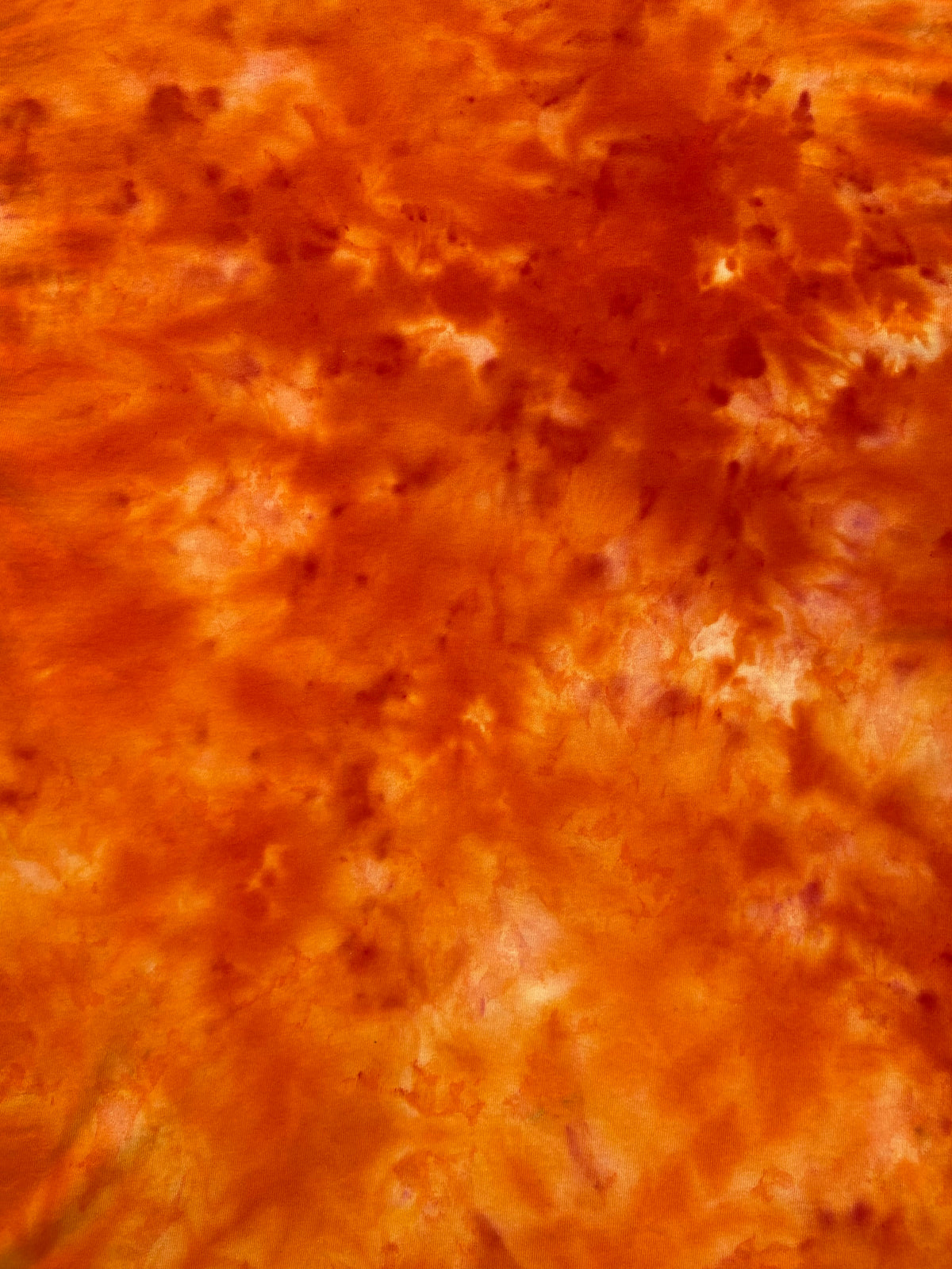 Close-up of Orange Sorbet Ice Scrunch tie dye fabric in vivid orange, burnt orange and lighter cream-toned patterns, individually hand dyed in the UK.