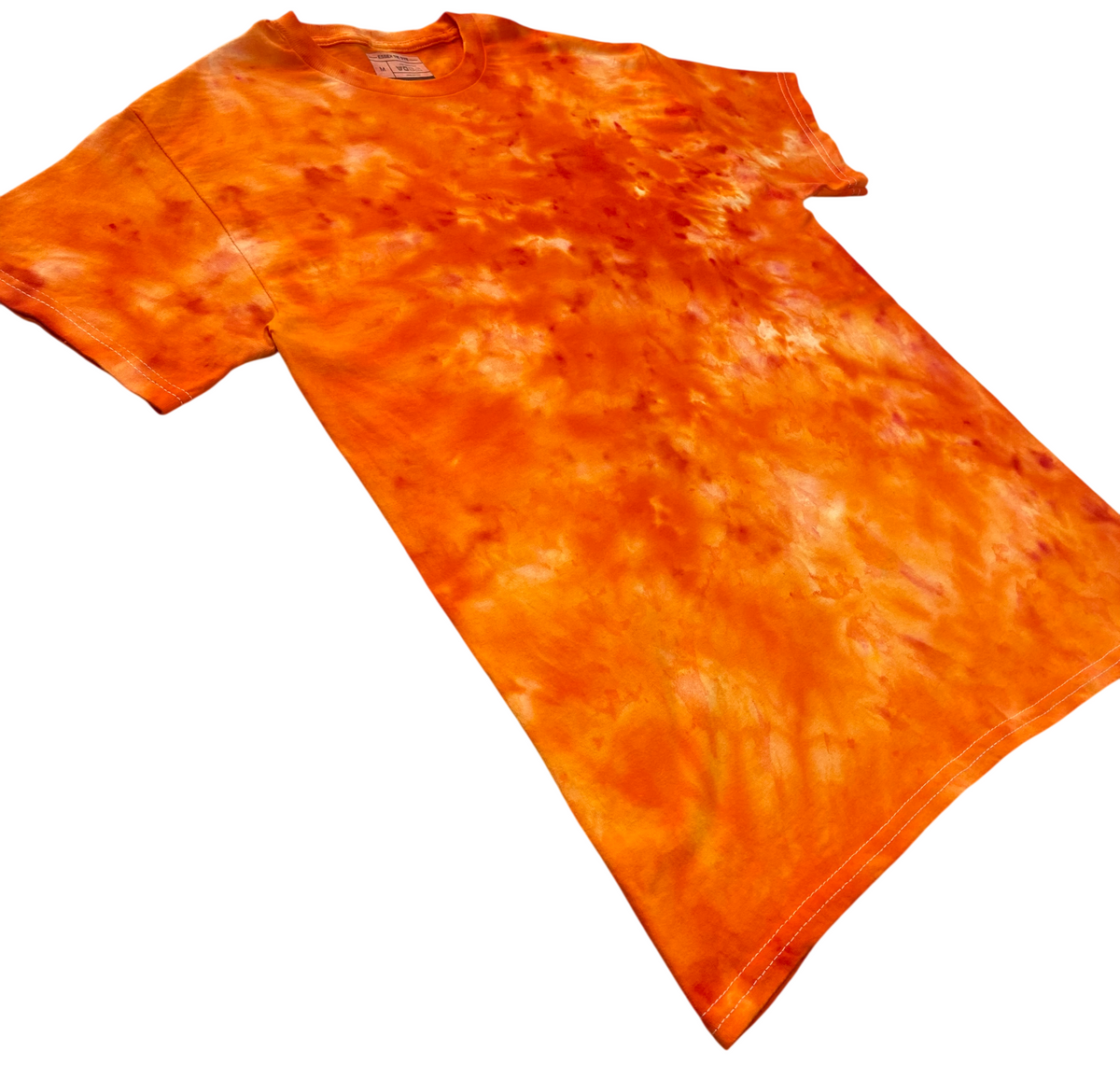 Orange Sorbet Ice Scrunch tie dye T-shirt shown at an angle, featuring vivid orange, burnt orange and lighter cream-toned hand-dyed patterns.