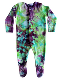 A baby long-sleeve footed sleeper with a vibrant green, purple, and teal tie-dye pattern, featuring a snap-button front closure.
