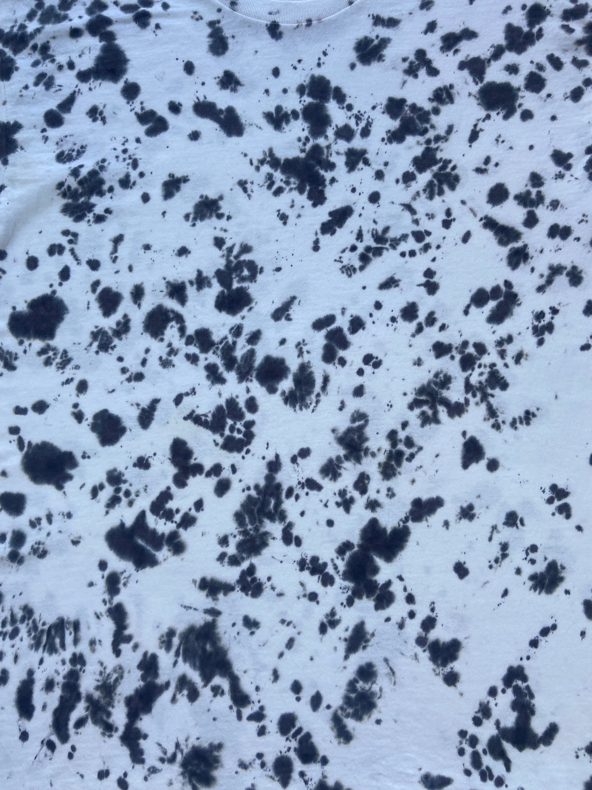 Close-up of Better Black Scrunch tie-dye fabric featuring a bold black splatter pattern on a pale grey-white background.