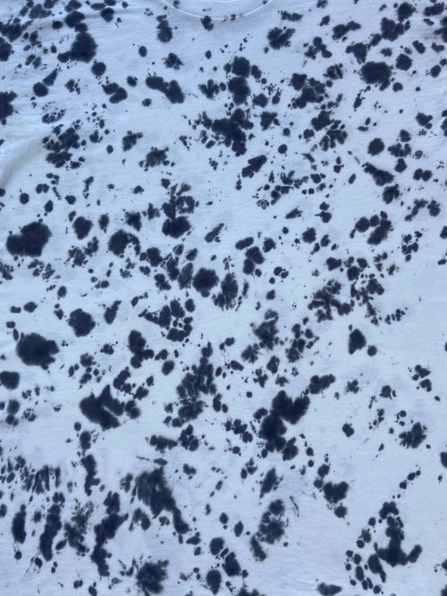 Close-up of Better Black Scrunch tie-dye fabric featuring a bold black splatter pattern on a pale grey-white background.