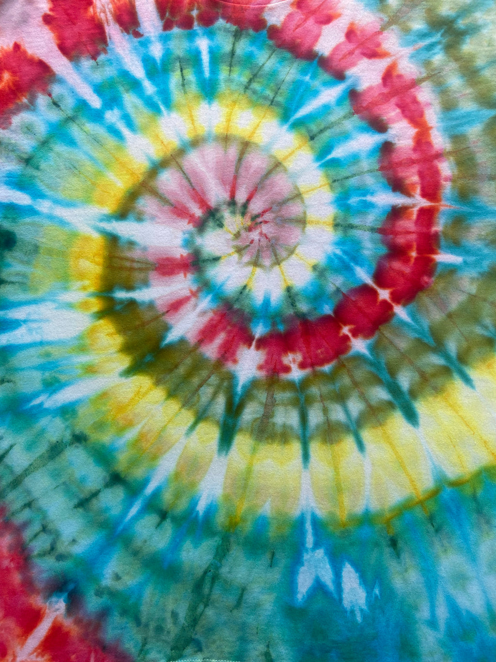 Close-up of a tie-dye pattern with concentric circles in red, yellow, green, and blue.