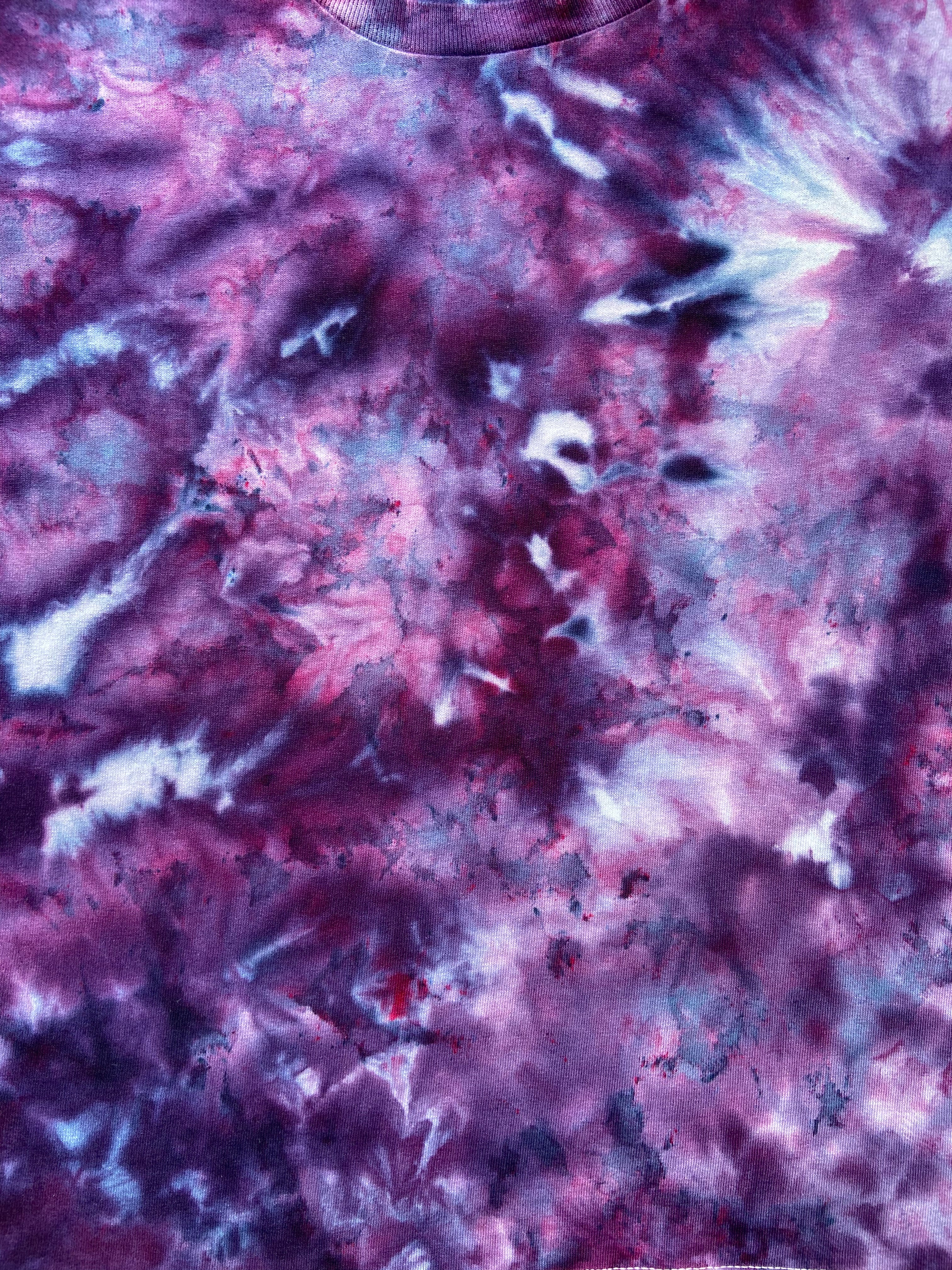 A close-up of a tie-dye fabric with a marbled pattern in shades of purple, pink, and white.