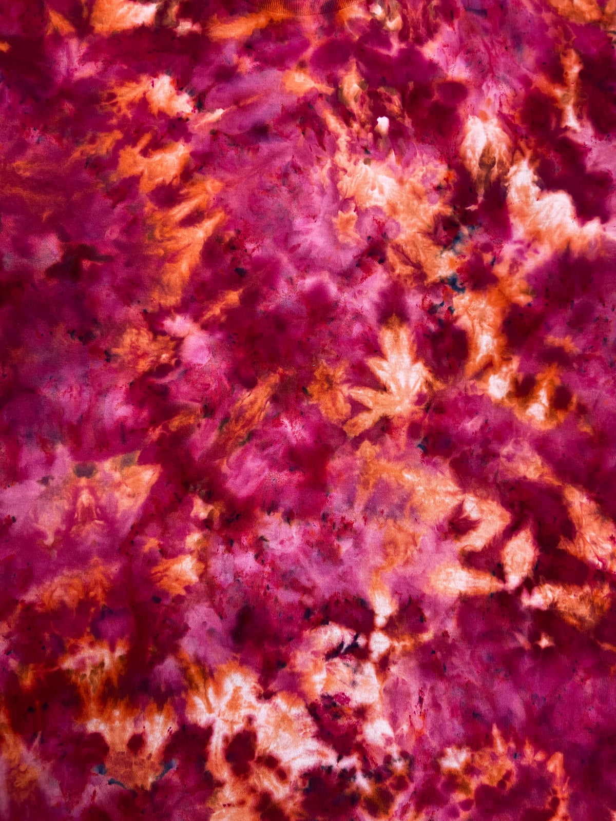 Close-up of the Pomegranate Ice tie-dye T-shirt showing rich magenta, berry, plum and peach-orange tie-dye detail.
