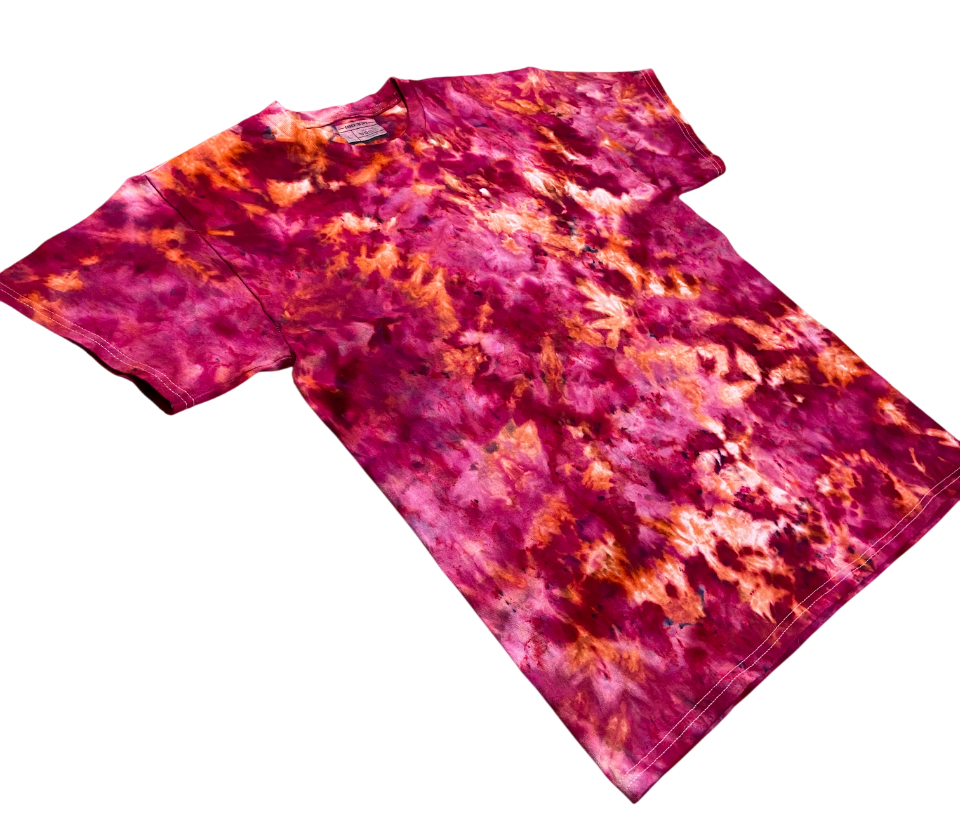 Angled view of the Pomegranate Ice tie-dye T-shirt featuring bold magenta, deep pink, plum and warm peach-orange marbled patterns.