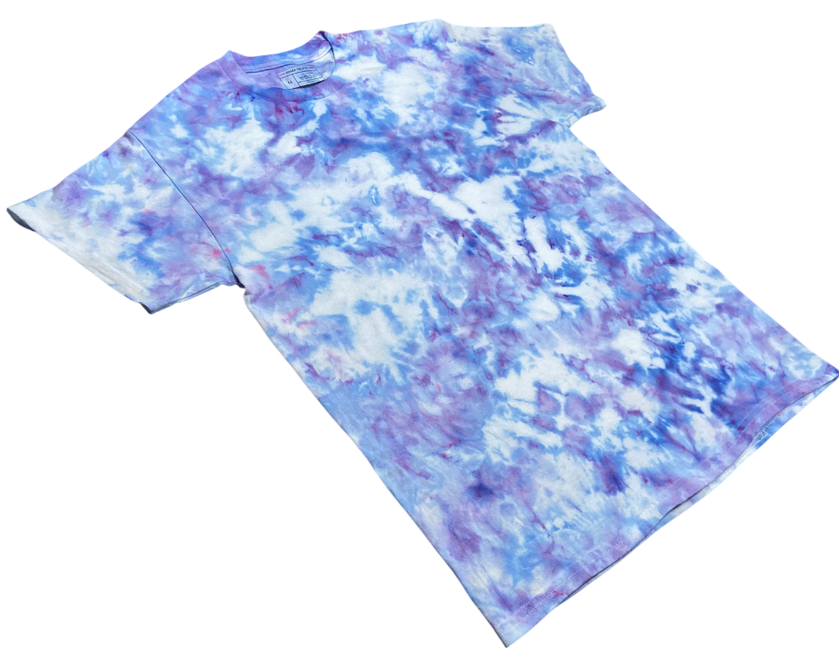 Ice Blue Ice Scrunch tie-dye T-shirt shown at an angle, featuring pale blue, purple and white organic ice-dyed patterns.