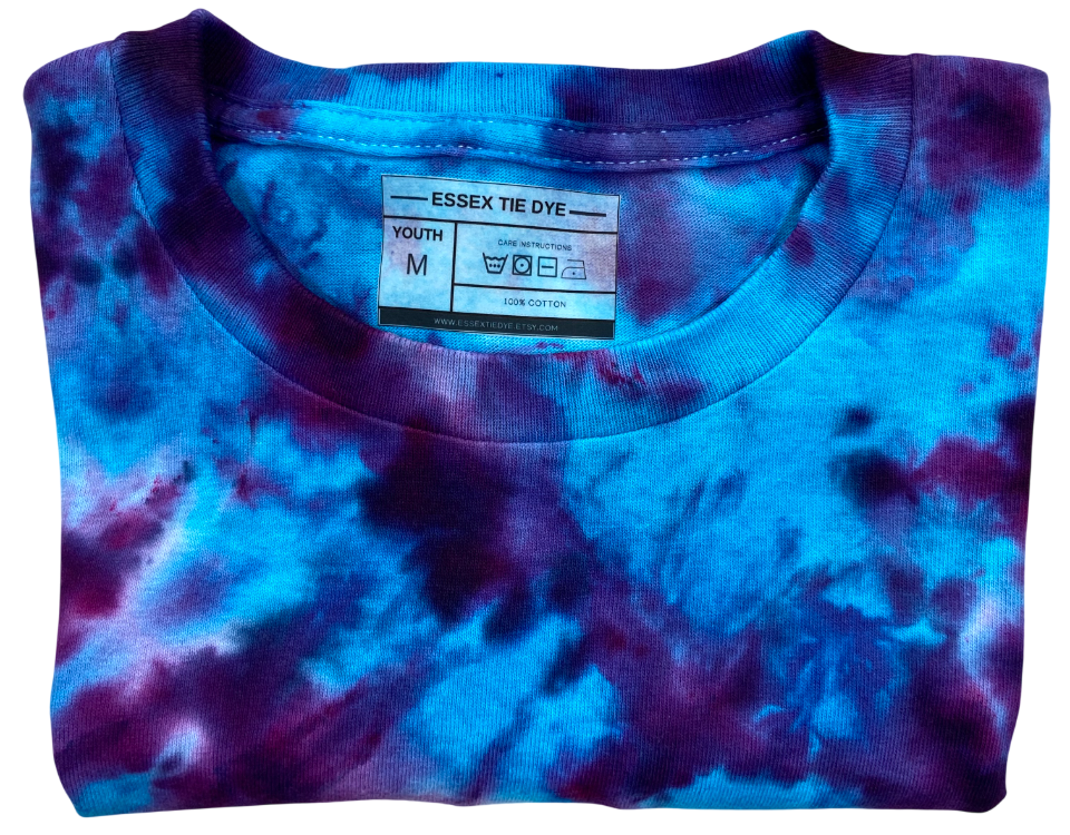 Folded tie-dye t-shirt with blue and purple patterns and a visible label on a white background.
