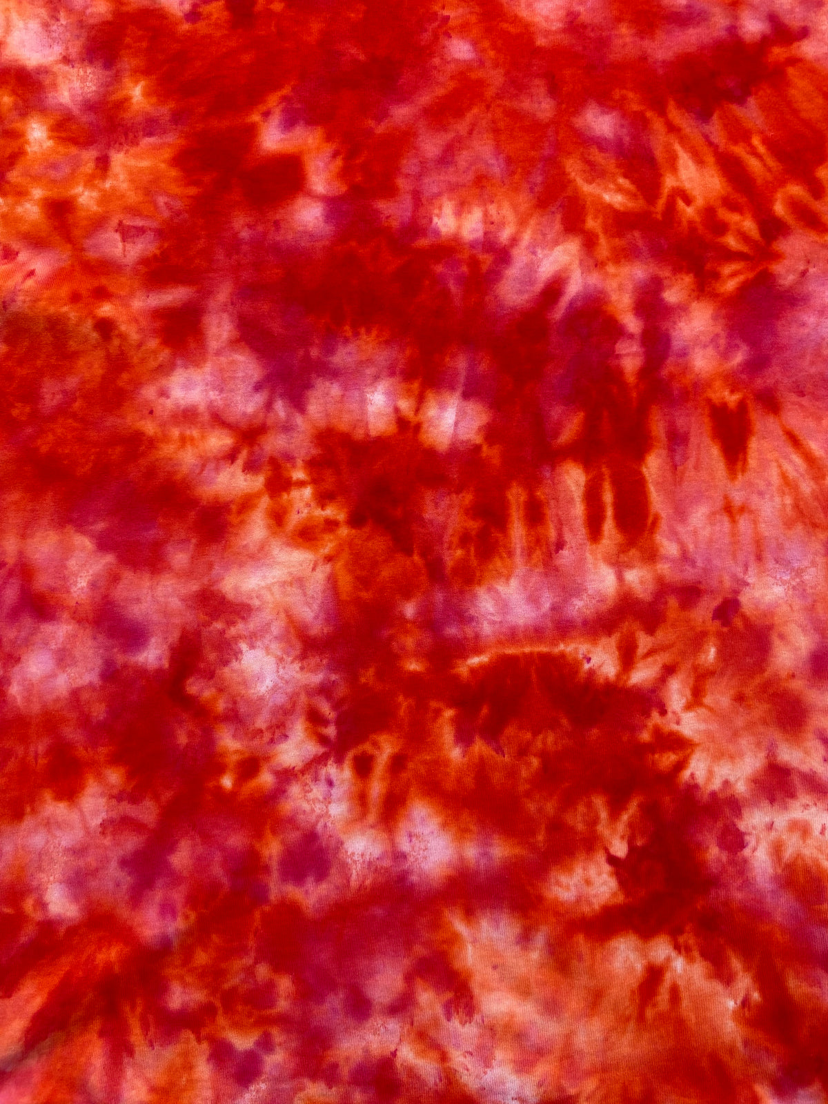 Close-up of Deep Orange Ice Scrunch tie-dye fabric featuring deep orange, red-orange and soft cream marbled patterns.