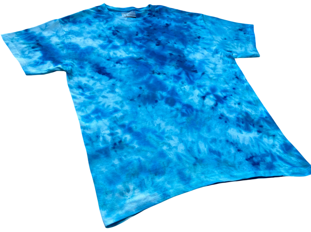 Caribbean Blue Ice Scrunch tie-dye T-shirt shown at an angle, featuring bright turquoise, aqua blue and deeper blue hand-dyed patterns.