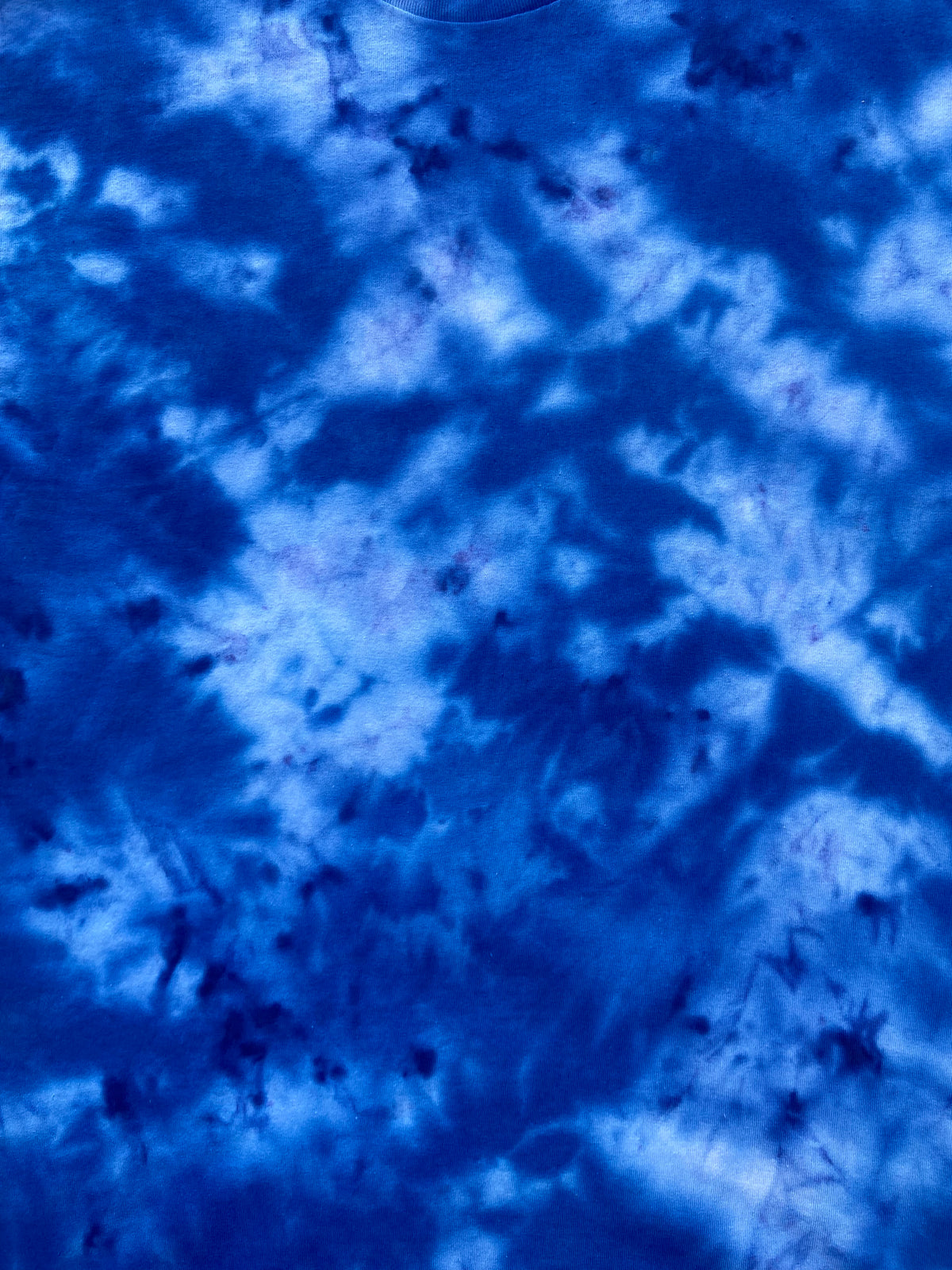 A close-up of a blue tie-dye pattern with swirling shades of royal blue, navy, and lighter icy blue.