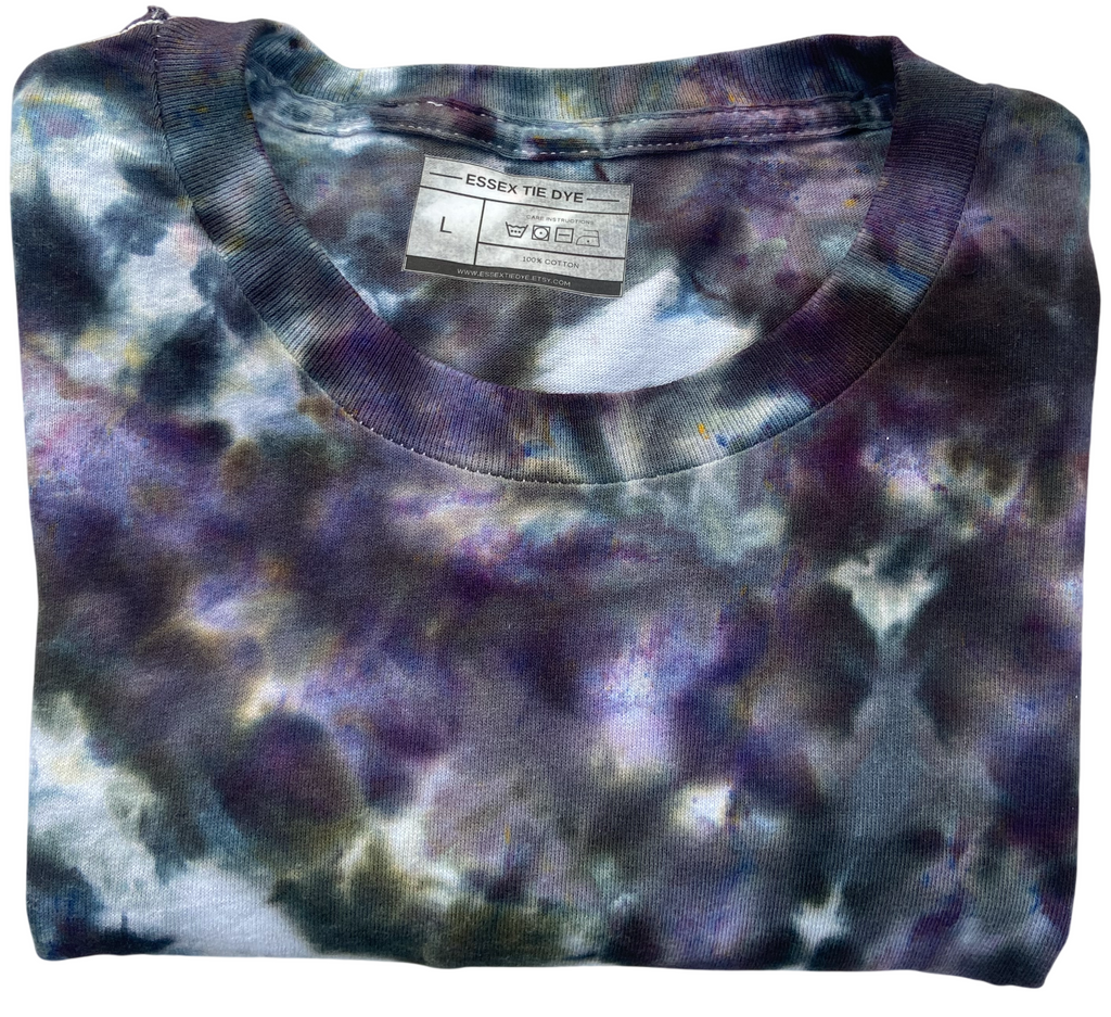 Folded tie-dye shirt of grey and purples with a visible Essex Tie Dye Label on a white background