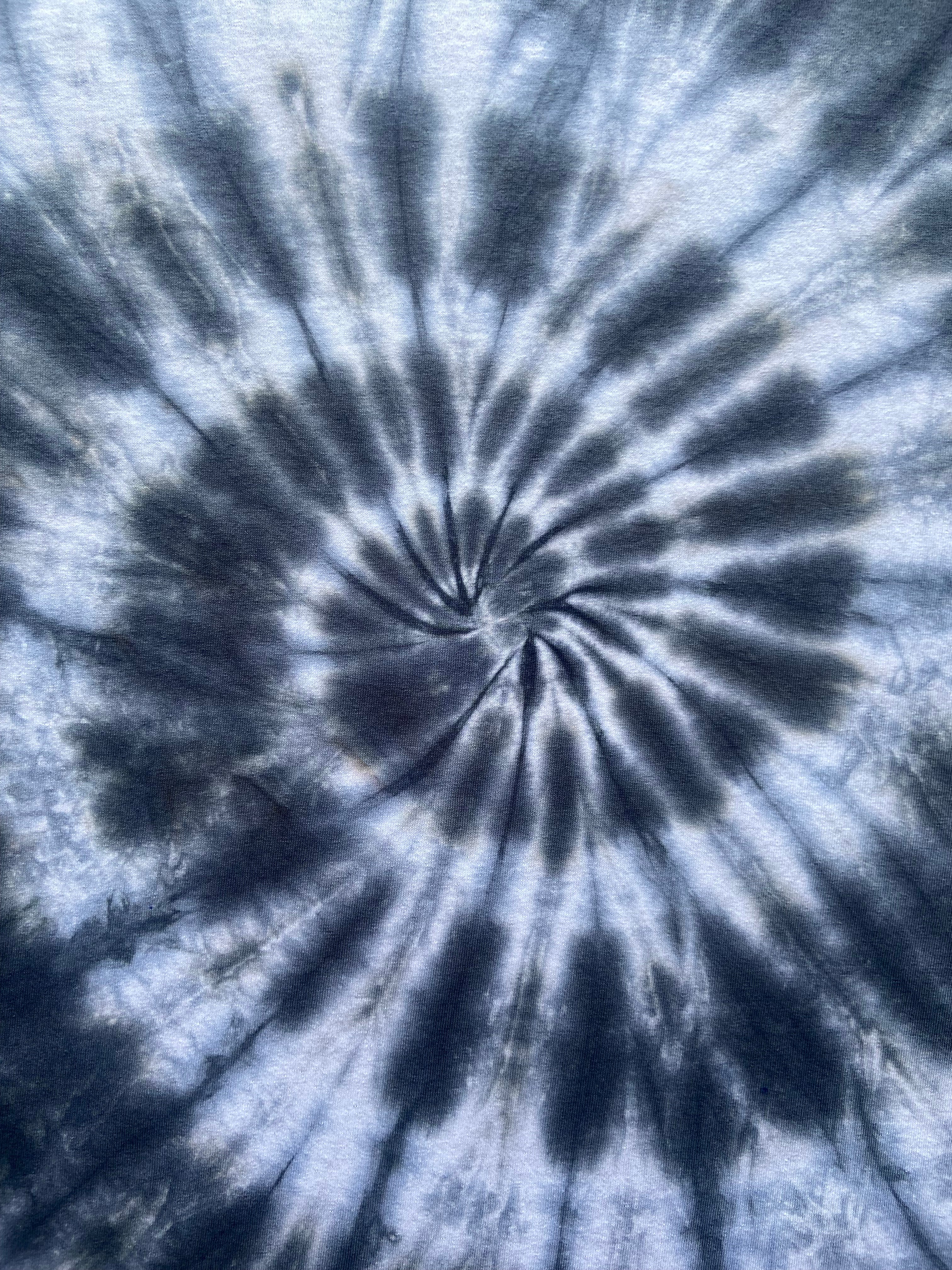 A close-up of a spiral tie-dye pattern in shades of blue, navy, and white, filling the entire frame.