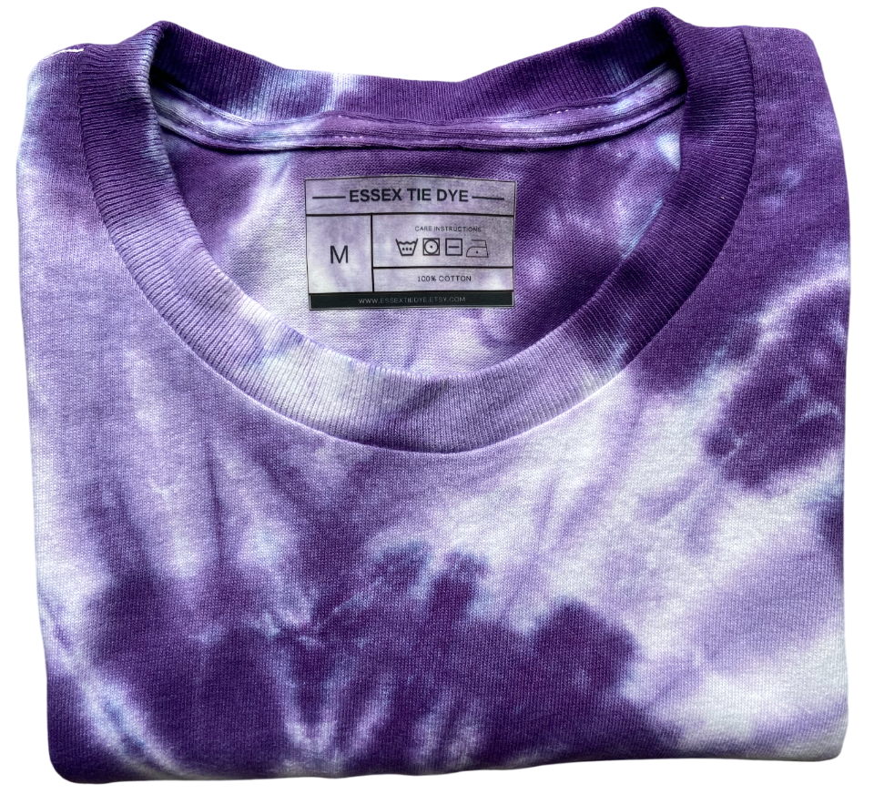A folded purple and white tie-dye t-shirt with a visible neck label reading 'ESSEX TIE DYE'.