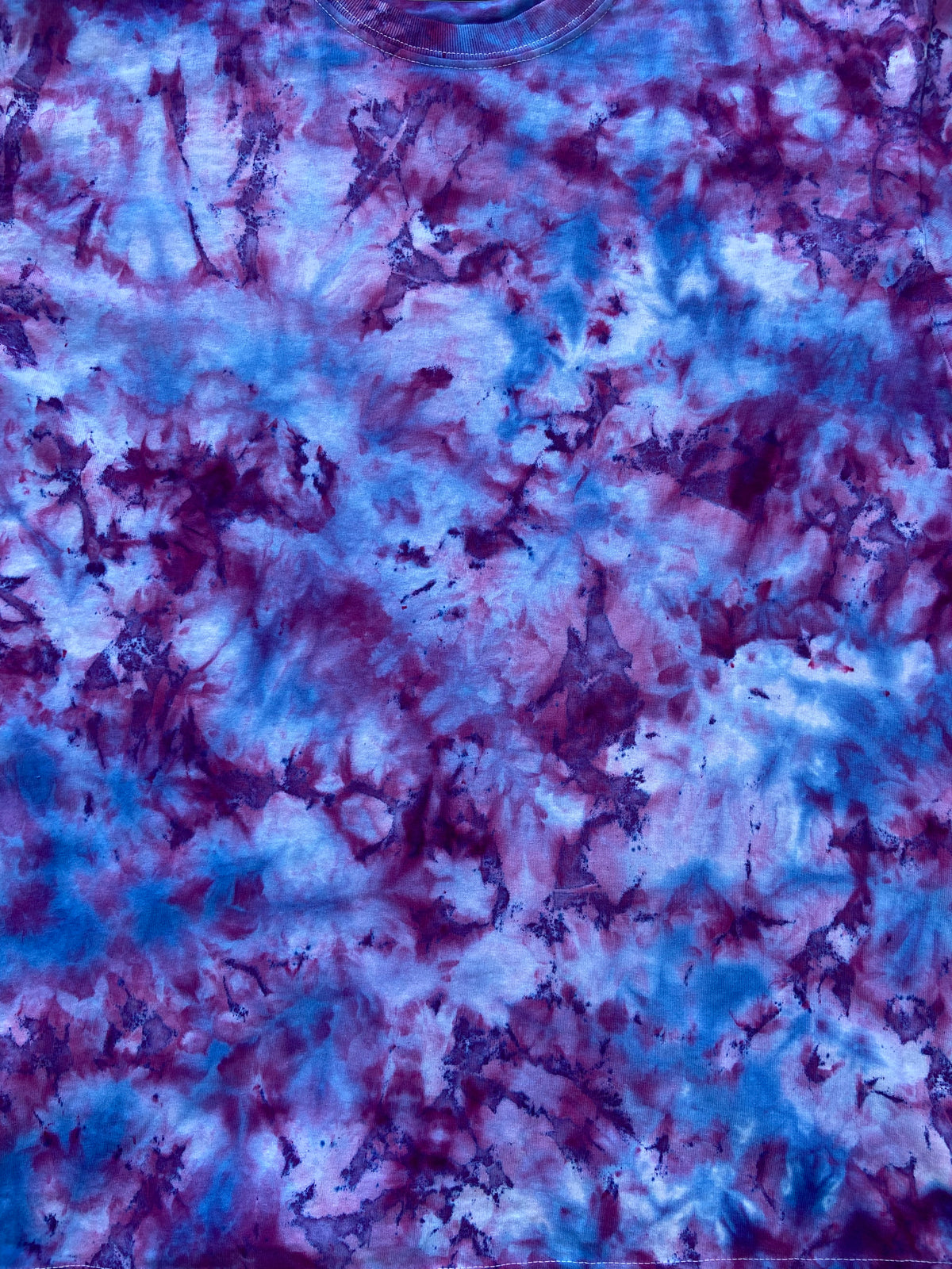 A close-up of a tie-dye fabric pattern featuring a marbled blend of blue, purple, and pink hues.