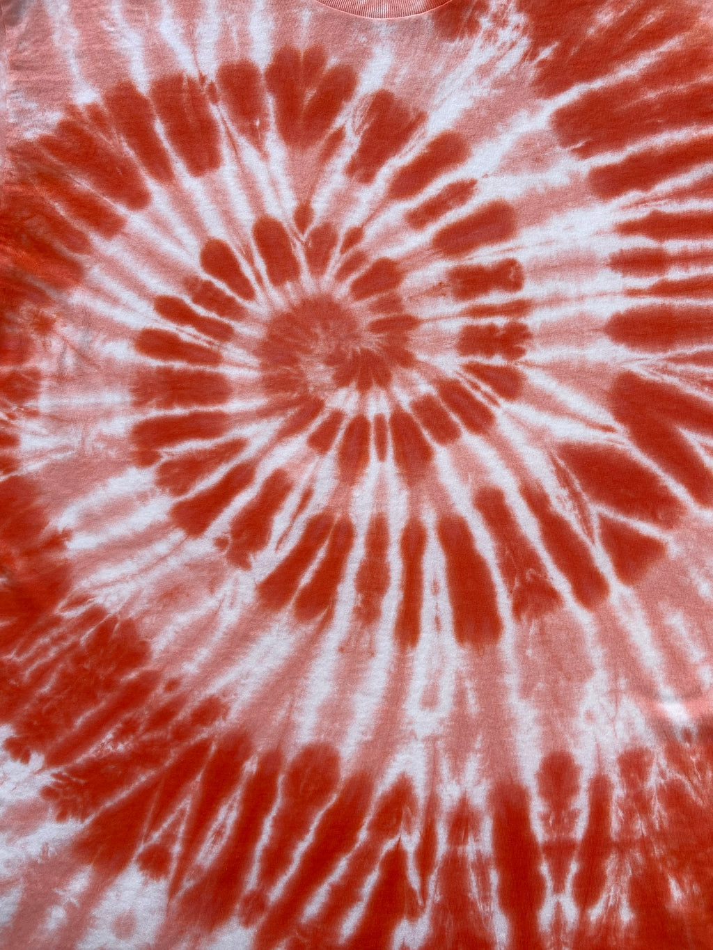 A close-up of a tie-dye pattern featuring a spiral design in vibrant red and white.