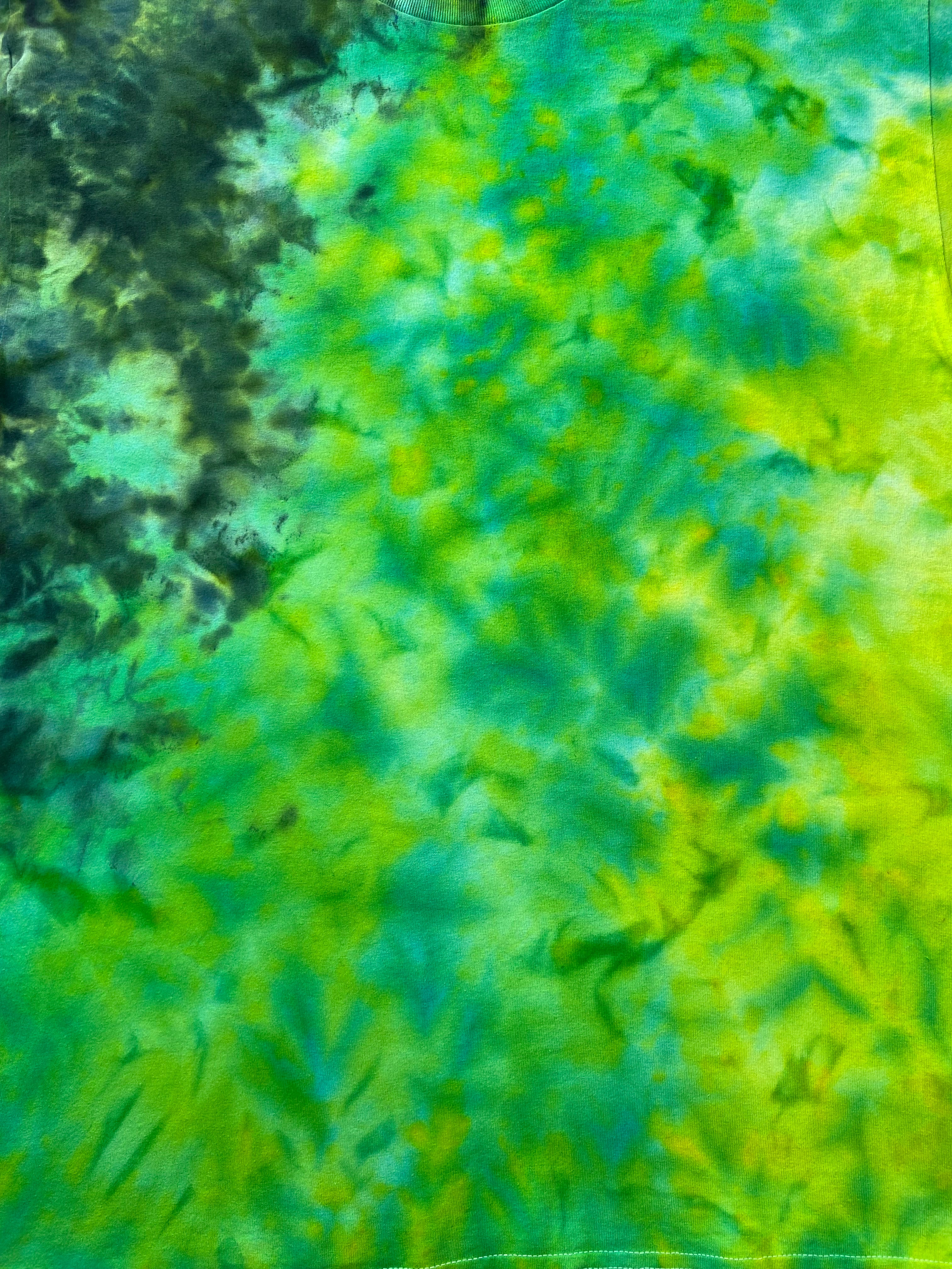 A close-up of a tie-dye fabric with a vibrant blend of green, yellow, and teal in a mottled pattern.