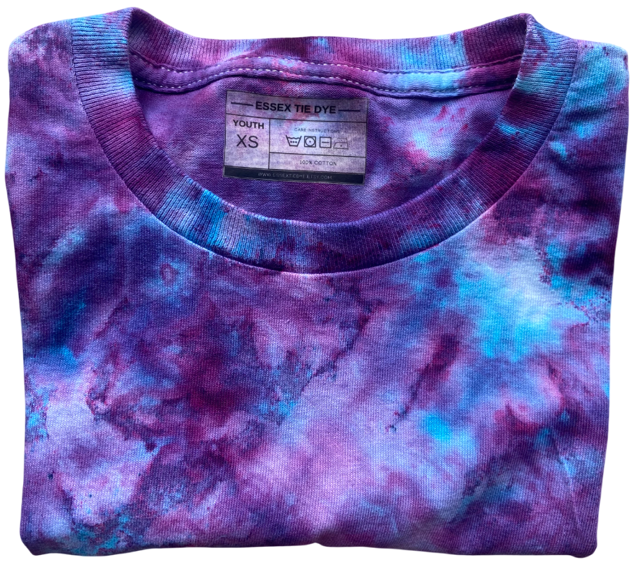 Folded purple and blue tie-dye shirt with a label on a white background